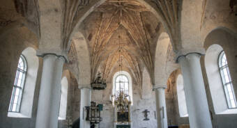 Insidan av S:t Petri kyrka. Det ljusa taket och väggarna pryds av målningar.