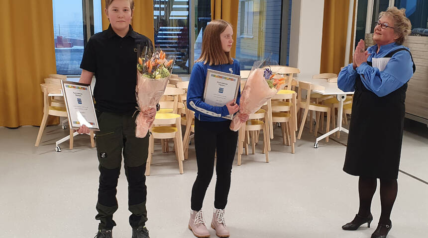 Kunnanvaltuuston puheenjohtaja Merja laaksonen oikealla onnittelemassa tyttöä ja poikaa heidän saamistaa parhaan urheilusuorituksen palkinnoista.