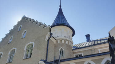 Suitian linnan suippokattoinen koristeellinen valko-harmaa torni, jonka huipussa on korkea piikki