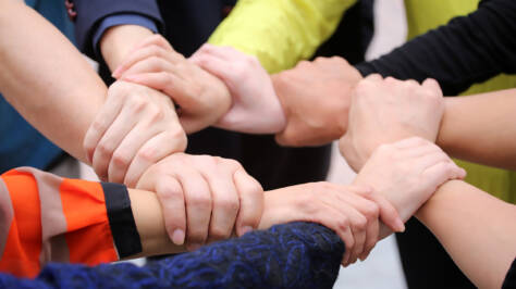 Åtta olika personers händer håller i varandra och bildar en ring.