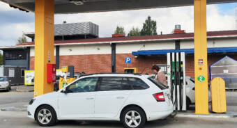 Nainen tankkaa autoaan bensa-asemalla.