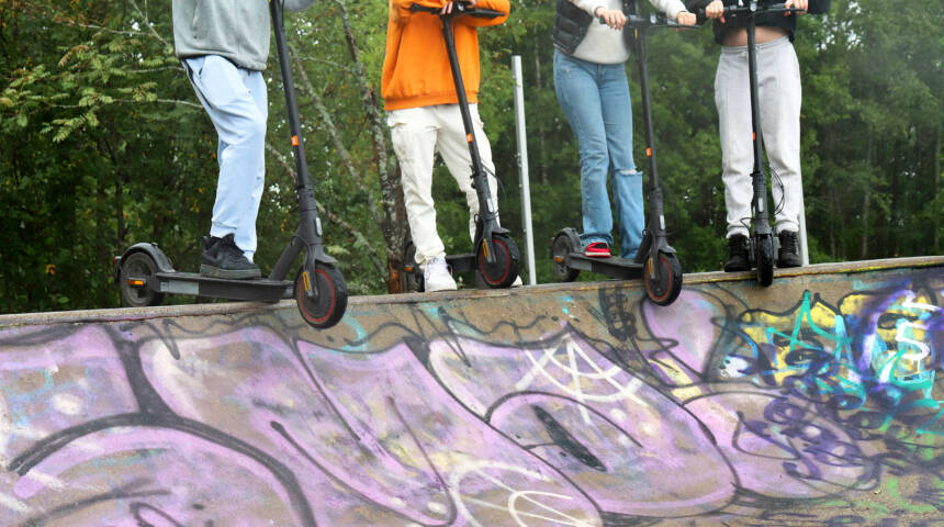 Fyra ungdomar med sina sparkbräden på kanten till en skateramp.
